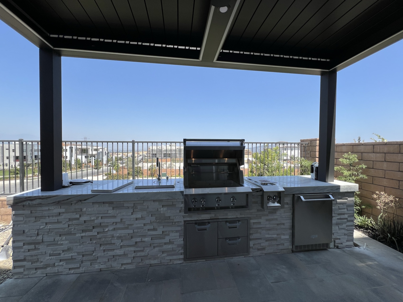 Built-in outdoor kitchen under a louvered pergola